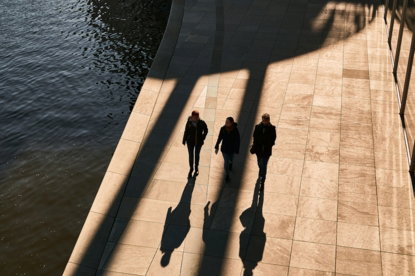 a group of people walking down a sidewalk next to a body of water